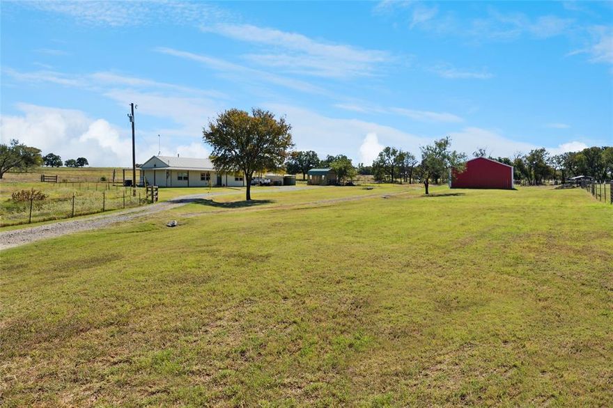 This beautifully maintained 3-bedroom, 2-bath barndominium offers peaceful country living with modern Texas charm. Situated on 1.637 acres, the home features approximately 1,800 square feet of open-concept living space with stained concrete floors, a cozy wood-burning stove, and abundant natural light. Built in 2017, the home includes a remodeled kitchen that serves as the centerpiece, showcasing granite countertops, a large island with bar seating, stainless-steel appliances, and generous cabinet storage. The primary suite provides a relaxing retreat with a dual-sink vanity, walk-in shower accented with subway tile, and a freestanding soaking tub. Enjoy quiet mornings or Texas sunsets from the covered wrap-around porch overlooking the spacious yard. The property includes a 30×40 workshop with electricity and a 10-foot overhang providing additional covered space for equipment or projects, a 12×20 outbuilding with power, ideal for hobbies or a home office, and a 25×30 covered carport for year-round vehicle protection. A circular driveway offers ample parking, while the metal roof and energy-efficient design add lasting value. Located just minutes from Weatherford and Mineral Wells and about 45 minutes from Fort Worth, this property perfectly blends rural serenity with modern comfort.
