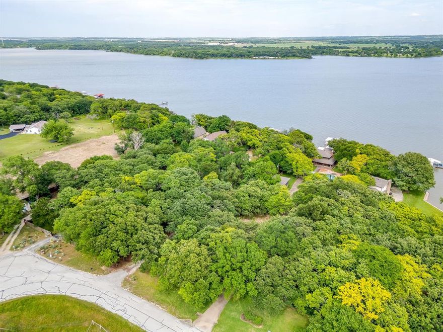 Welcome to a rare waterfront opportunity on 1.22 acres along the open waters of Eagle Mountain Lake. Tucked behind a beautifully tree lined gated entrance, this private and fenced property offers a peaceful retreat surrounded by towering mature trees, expansive lake views, and the serenity of nature. The setting is truly special, with a long gated drive creating a sense of arrival while providing both privacy and seclusion.  Positioned on deep open water, the property captures breathtaking panoramic views and offers direct access to the lake for boating, fishing, and recreation. Multiple outdoor spaces allow you to enjoy the scenery, shade, and tranquil atmosphere created by the abundance of mature trees surrounding the property. Whether you are looking for a weekend escape, future dream home site, or a full time waterfront lifestyle, the land itself is the true highlight of this property.  The property includes a main house with two bedrooms, two baths, multiple living areas, and lake facing windows that maximize the waterfront views. A separate guest house with kitchen and full bath provides additional flexibility for guests, rental potential, or multigenerational living. Storage buildings and additional improvements offer functionality and convenience while leaving ample room to personalize the property to your vision.  With gated access, fencing, mature landscaping, open water frontage, and endless potential, this Eagle Mountain Lake property presents a unique opportunity to own a private slice of waterfront paradise in one of the lake’s most desirable areas.  Call for your private showing today!