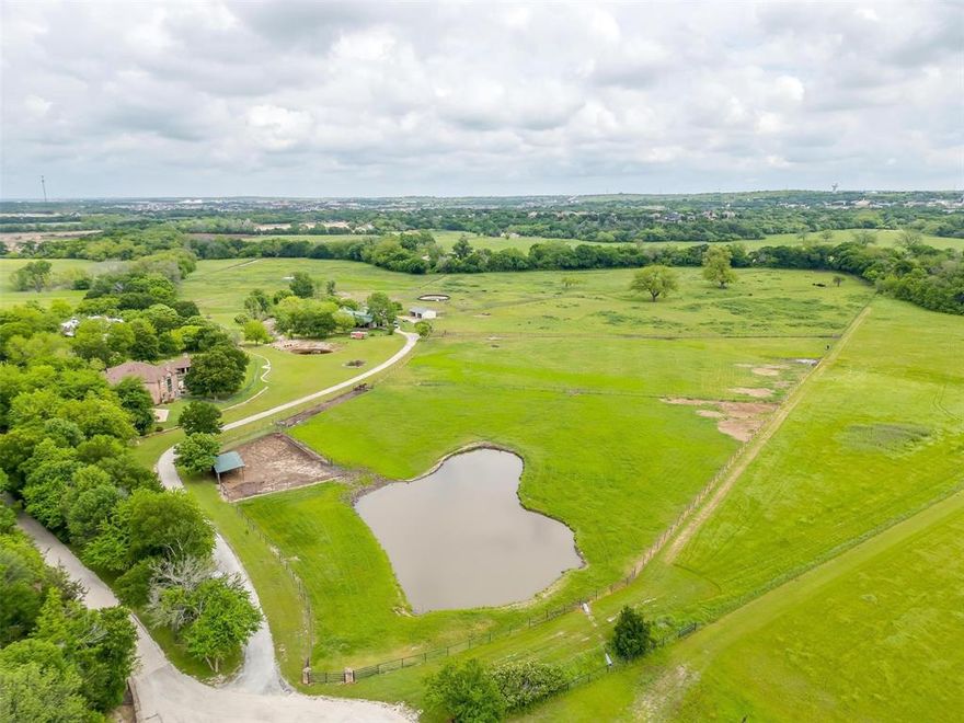 Just over 30 acres and more than 5,000 square feet of luxurious living space located just outside downtown Aledo! Experience the epitome of grandeur at this elegant residence, with soaring ceilings, large picture windows and multiple living spaces, creating a sense of spacious elegance and comfort. The beautiful manicured and cross fenced land spanning over 30 acres is a true haven for anyone hoping to raise or train horses. The property boasts a horse barn with 11 stalls, serene paddocks, and even a stone bridge. There is also a guest home on the property, which is over 2,000 square feet. The back portion of the property boarders the winding Trinity, providing privacy and serenity. Enjoy leisurely afternoons by the pool, surrounded by the breathtaking scenery of this private estate. This is an exceptional opportunity to embrace the country lifestyle, as well as the enjoyment of grandeur and sophistication this wonderful home provides all just minutes from the heart of Aledo, TX.
