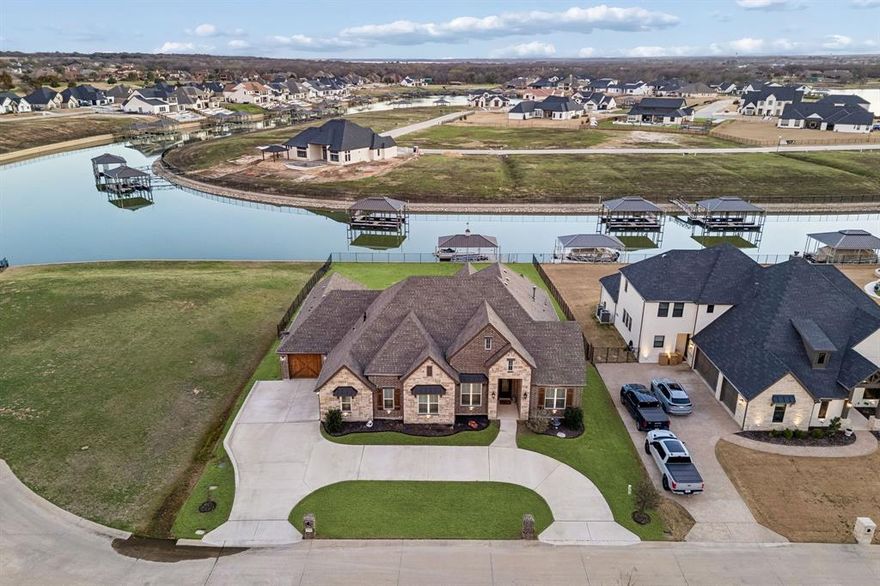 This stunning single story custom waterfront home is located in The Resort on Eagle Mountain Lake. The only 24-7 gated and guarded golf course community on Eagle Mountain Lake. Built in 2021, the home offers 4 spacious bedrooms, 4 full bathrooms, a dedicated office, and a versatile game room or flex space. The thoughtfully designed open concept layout seamlessly connects the  kitchen, dining area, and living room, where sliding glass doors frame serene canal views and create effortless indoor and outdoor living. The chef’s kitchen features marble stone countertops, a built in commercial grade refrigerator, gas range, walk in pantry, and custom cabinetry. The primary suite overlooks the water and offers a spa inspired en suite bath along with a walk in closet. A secondary master suite is located on the other side of the home with canal views, large en-suite bath and walk in closet. Two additional guest bedrooms are well appointed, one having an en-suite bath and the other convenient powder bath for visitors. The dedicated office, complete with French doors, overlooks both the living area and the canal, providing an inspiring work from home setting. The flex room currently being used as a gym has direct access to the patio as well. Step outside to a backyard ready for your vision, whether it’s a resort style pool, extended patio, or outdoor retreat. Your private boat dock includes both a boat lift and jet ski lift, making lakeside living effortless and enjoyable year round. Notable upgrades include two tankless water heaters, a circular driveway, surround sound in the living and game rooms, and custom plantation shutters throughout. Residents of The Resort enjoy unmatched amenities, including a 19-hole golf course, clubhouse with restaurant and bar, two pools, fitness center, playground, sports courts, private beach with pergolas, boat ramp, and more. This is a rare opportunity to own a waterfront property in one of Eagle Mountain Lake’s most exclusive communities.