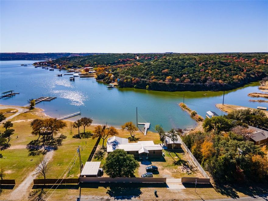 The perfect family lake setting. Immaculate lakefront home w log facia, metal roof and wonderful lake views. Conveniently located close to Bass Hollow and The Breakers Marina on the Westside of Possum Kingdom Lake. Big lakeside yard with beautiful trees. Relax on the large covered back porch. Gentle slope large backyard and private shoreline. Floating PWC EZ dock. Split bedroom plan for privacy, living area with lake views, large family game room or bunk room with fireplace & sink. Numerous recent upgrades… spray foam beneath home, Pex plumbing, sewer line, hot water heater, window screens, renovated 2nd bath shower & vanity, and upgrade vinyl plank flooring in kitchen & living. Detached insulated workshop or storage, floating PWC dock, new cement shoreline patio. Covered boat storage and abundant parking. Roadside metal privacy fence with electric gate for privacy. You will be hard pressed to find another lakefront property with such value and smart lake living.