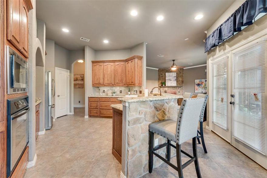 Welcome to this exceptional custom-built home, nestled on a 1-acre lot in the exclusive, gated community of Rose Creek Estates—offering privacy, luxury, and NO city taxes. Located outside city limits, this home provides the perfect blend of tranquility and convenience. Upon entry, you’re greeted by soaring ceilings, a grand staircase, and elegant hardwood floors that flow through the formal study and dining room—both flooded with natural light from large windows. The spacious living area features a dramatic floor-to-ceiling stacked stone wood-burning fireplace and a wall of windows framing serene backyard views. The gourmet kitchen is a chef’s dream, showcasing stainless steel appliances, granite countertops, abundant cabinetry, a brick-detailed cooktop surround, walk-in pantry, breakfast bar, and cozy breakfast nook with more stunning views. The luxurious primary suite on the main floor boasts vaulted ceilings, bay windows, private patio access, and a spa-inspired en-suite with jetted tub, oversized walk-in shower, dual vanities, and a massive walk-in closet. An additional guest bedroom is located on the main level, while all secondary bedrooms are upstairs—each with ensuite bathrooms. The upper floor also includes a media room and large game room, perfect for entertaining. Step outside to your own private oasis: a huge covered patio with ceiling fans, a beautifully landscaped yard, and wrought iron fencing—ideal for relaxing or hosting gatherings. New Roof 2023, New HVAC 2024