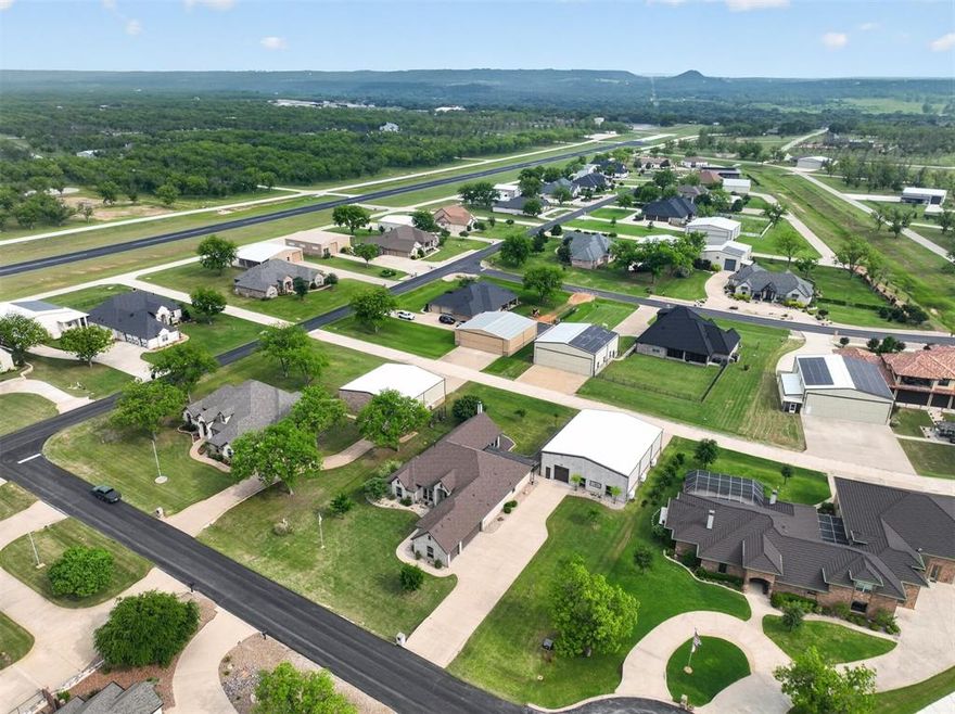 This exceptional custom home is located behind the gates of Pecan Plantation, in The Landings Airpark, FAA Identifier 66TE, with a direct concrete taxiway, RNAV approach, pilot controlled lighting, & VASI. The 50 x 60 hangar spans 3,000 square feet, is fully heated & cooled with hard cell foam insulation, textured epoxy flooring, MacroAir fan, color changing backlighting, sink, storage room, & hidden storage for a clean space. The workshop includes a full bath, 220V commercial plug, 110 amp service, air compressor with three hookups, built in dust collection, speakers, & storage. The SCHWEISS bifold door opens 42 feet wide with 10'10 ft clearance. (Replacement cost for a similar hangar is estimated around 300K). Above the workshop, separated by a sound insulated wall, is a fully finished 463 square foot apartment with a king size bedroom, full bath, living area, & kitchen. This is a true apartment, not guest quarters, with full separation from the main home, ideal for multi-generational living. The main residence offers 3,711 sq ft with an open layout & elevated finishes including hardwood flooring, granite surfaces, upgraded lighting, & custom details. The home features 3 bedrooms, 2 full baths, & one half bath, with each guest bedroom offering its own vanity & sink. A 294 square foot bonus room with a walk in closet & sink can serve as a 4th bedroom, office, or media space. The primary suite connects through the oversized closet directly to the utility room. Additional highlights include a two year old roof, tankless water heater, foam insulation, new dishwasher, French drains, generator hookup in the three car garage, stained concrete, covered walkways to the hangar, & landscaping. The layout keeps the hangar & home connected so your aircraft, RV, boat, & equipment are part of your daily routine. More than a hangar, more than a home, it’s the lifestyle you deserve! Property videos and 3D tours available! Visit ppoaweb.com to explore the community.