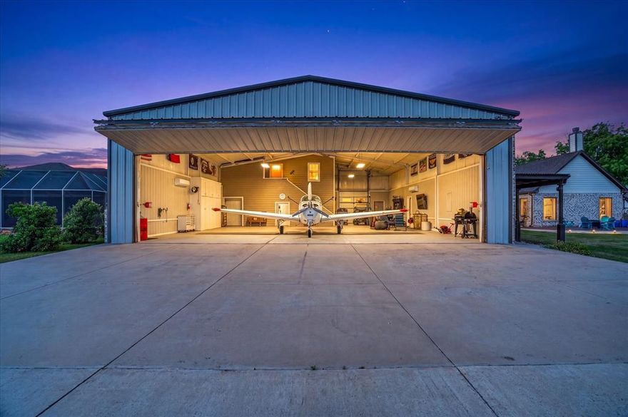 This exceptional custom home is located behind the gates of Pecan Plantation, in The Landings Airpark, FAA Identifier 66TE, with a direct concrete taxiway, RNAV approach, pilot controlled lighting, & VASI. The 50 x 60 hangar spans 3,000 square feet, is fully heated & cooled with hard cell foam insulation, textured epoxy flooring, MacroAir fan, color changing backlighting, sink, storage room, & hidden storage for a clean space. The workshop includes a full bath, 220V commercial plug, 110 amp service, air compressor with three hookups, built in dust collection, speakers, & storage. The SCHWEISS bifold door opens 42 feet wide with 10'10 ft clearance. (Replacement cost for a similar hangar is estimated around 300K). Above the workshop, separated by a sound insulated wall, is a fully finished 463 square foot apartment with a king size bedroom, full bath, living area, & kitchen. This is a true apartment, not guest quarters, with full separation from the main home, ideal for multi-generational living. The main residence offers 3,711 sq ft with an open layout & elevated finishes including hardwood flooring, granite surfaces, upgraded lighting, & custom details. The home features 3 bedrooms, 2 full baths, & one half bath, with each guest bedroom offering its own vanity & sink. A 294 square foot bonus room with a walk in closet & sink can serve as a 4th bedroom, office, or media space. The primary suite connects through the oversized closet directly to the utility room. Additional highlights include a two year old roof, tankless water heater, foam insulation, new dishwasher, French drains, generator hookup in the three car garage, stained concrete, covered walkways to the hangar, & landscaping. The layout keeps the hangar & home connected so your aircraft, RV, boat, & equipment are part of your daily routine. More than a hangar, more than a home, it’s the lifestyle you deserve! Property videos and 3D tours available! Visit ppoaweb.com to explore the community.
