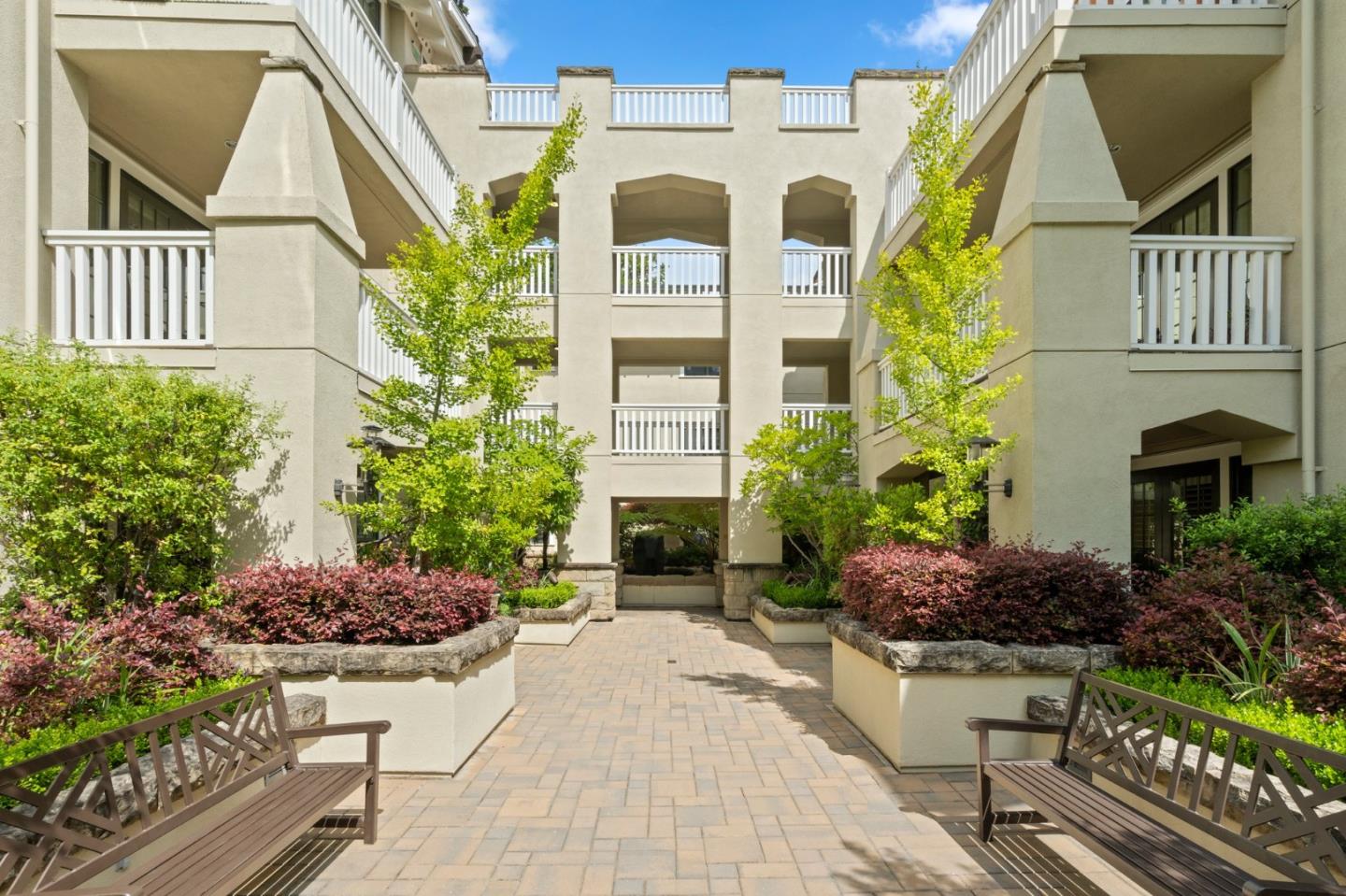 Residential building courtyard with raised garden beds, paved walkway, and benches.