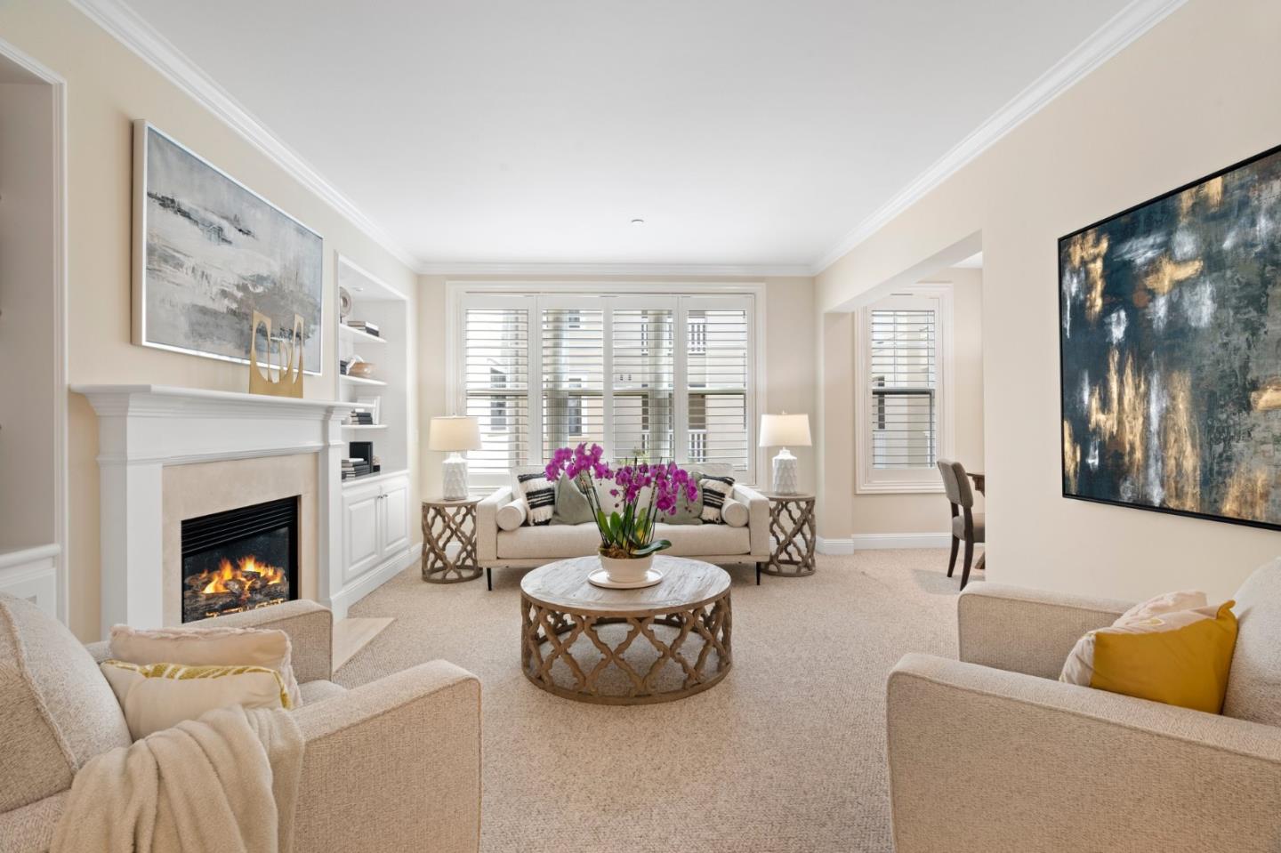 Living room with a fireplace, plantation shutters, and purple orchids on the coffee table.