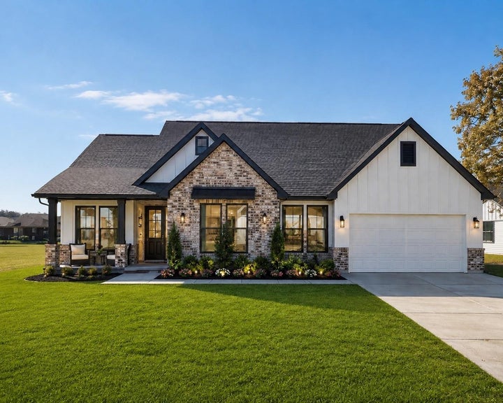 This aerial view showcases a charming home with a black roof and spacious front lawn. It features a wide driveway…
