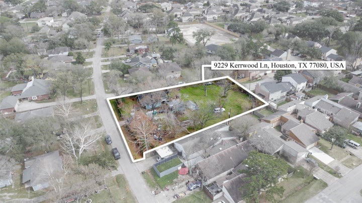 Lower-altitude aerial view providing a clearer look at the interior of the lot, including open buildable space and tree…