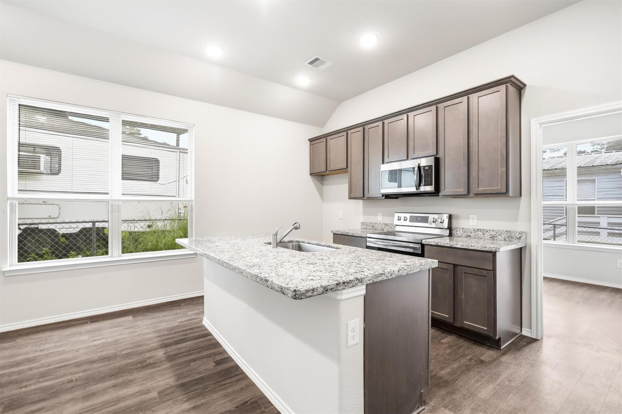 From this angle you can really appreciate the granite countertop on the peninsula and the sink's positioning ? it keeps whoever's cooking connected to the living space rather than tucked away. Windows on two sides of the kitchen mean you've got natural light coming in from multiple directions throughout the day.