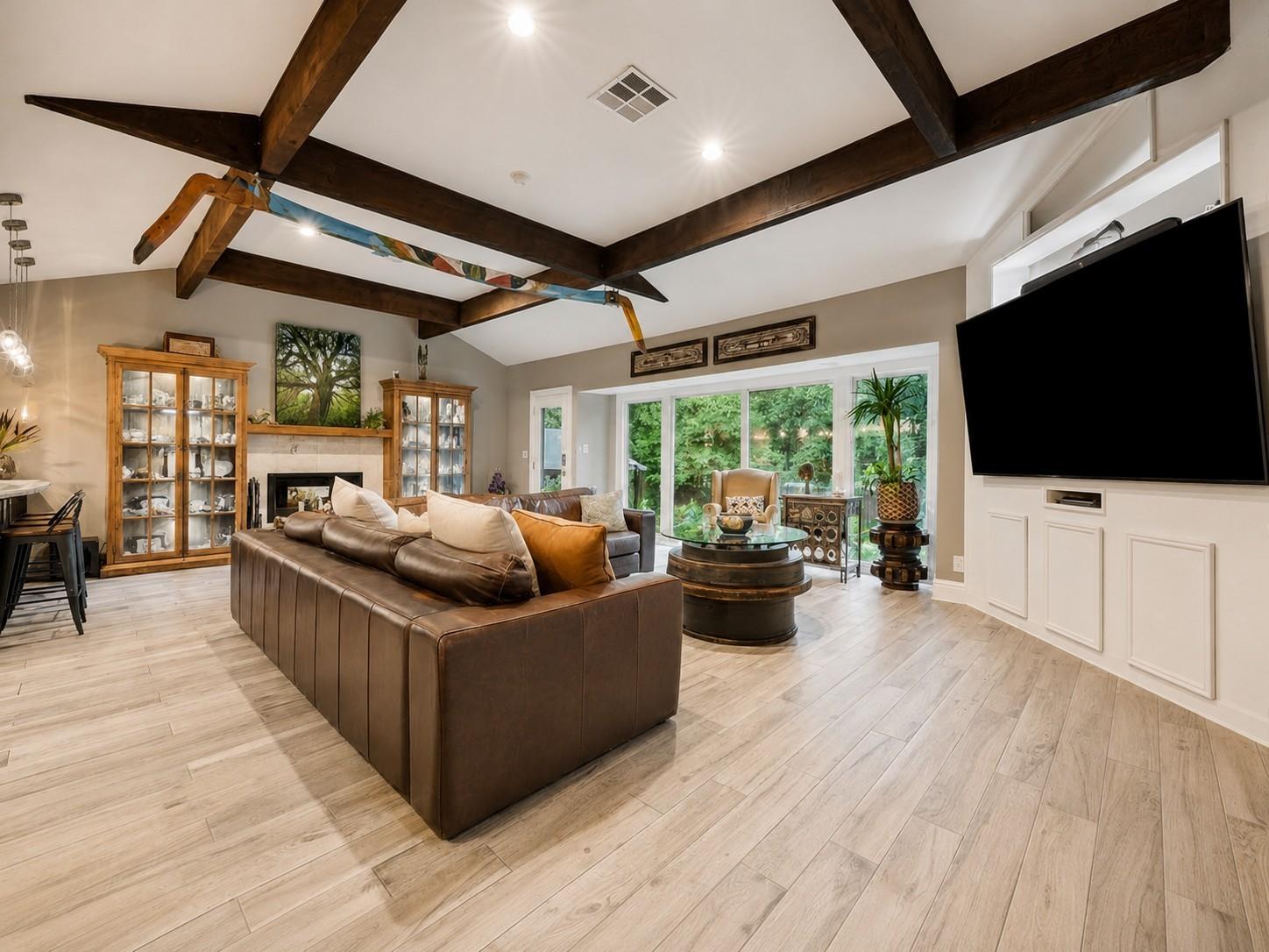 Spacious family room with vaulted ceilings, custom wood beams, recessed lighting, and large picture windows for the perfect view of the resort-style backyard oasis.