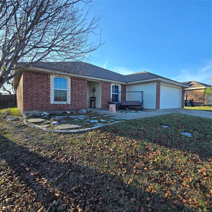 Single story home featuring brick siding, a patio, driveway, and a garage