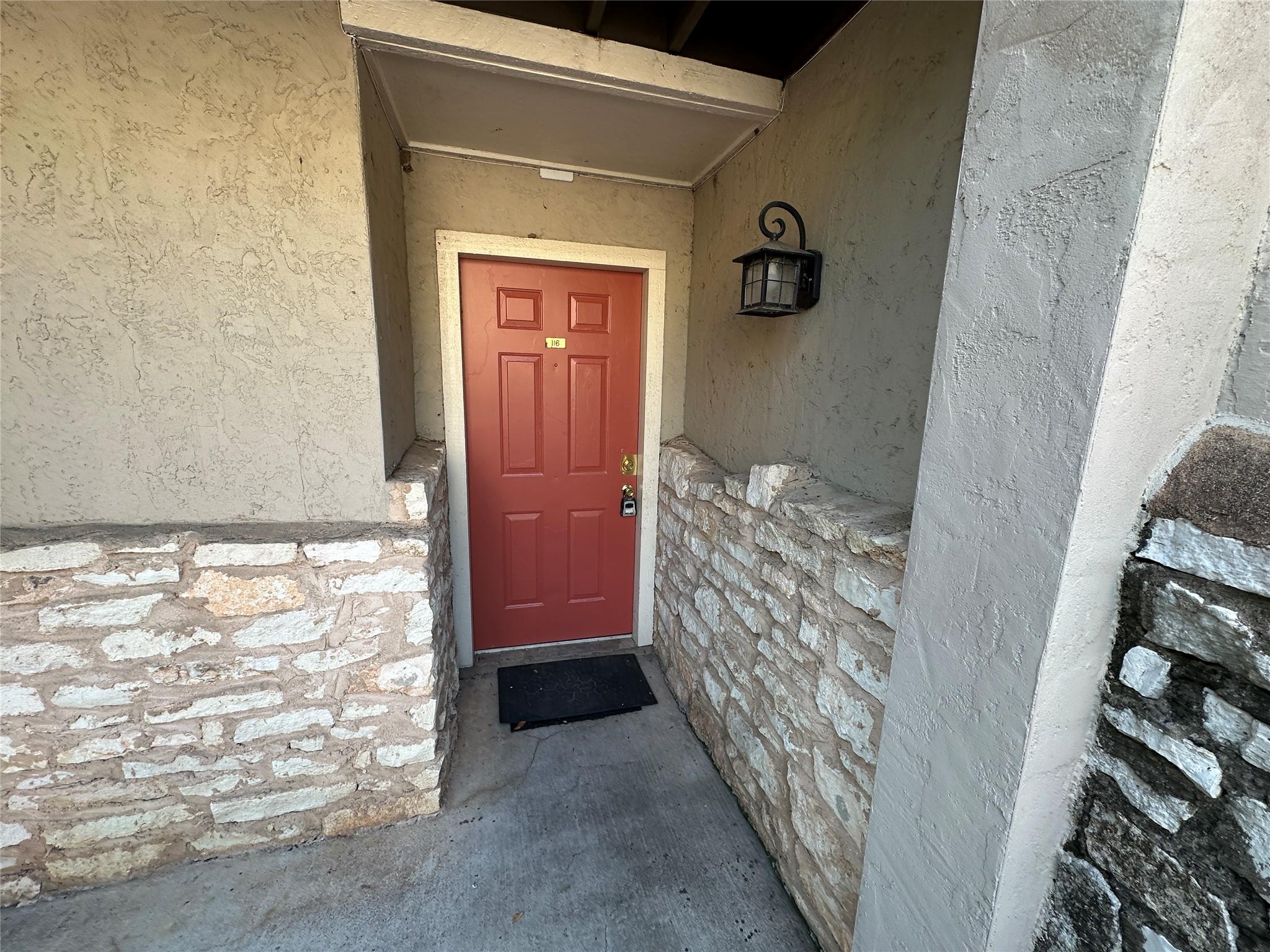 Entryway with a paneled red door, stucco exterior