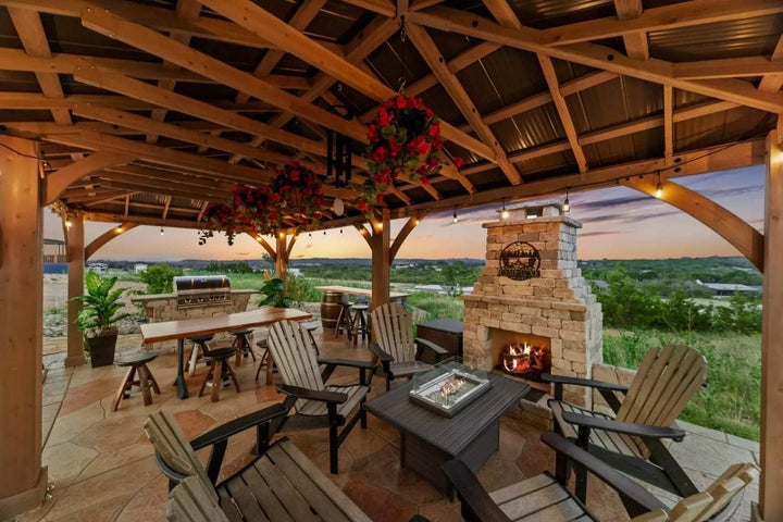 View of patio / terrace with an outdoor stone fireplace, outdoor dining area, and area for grilling