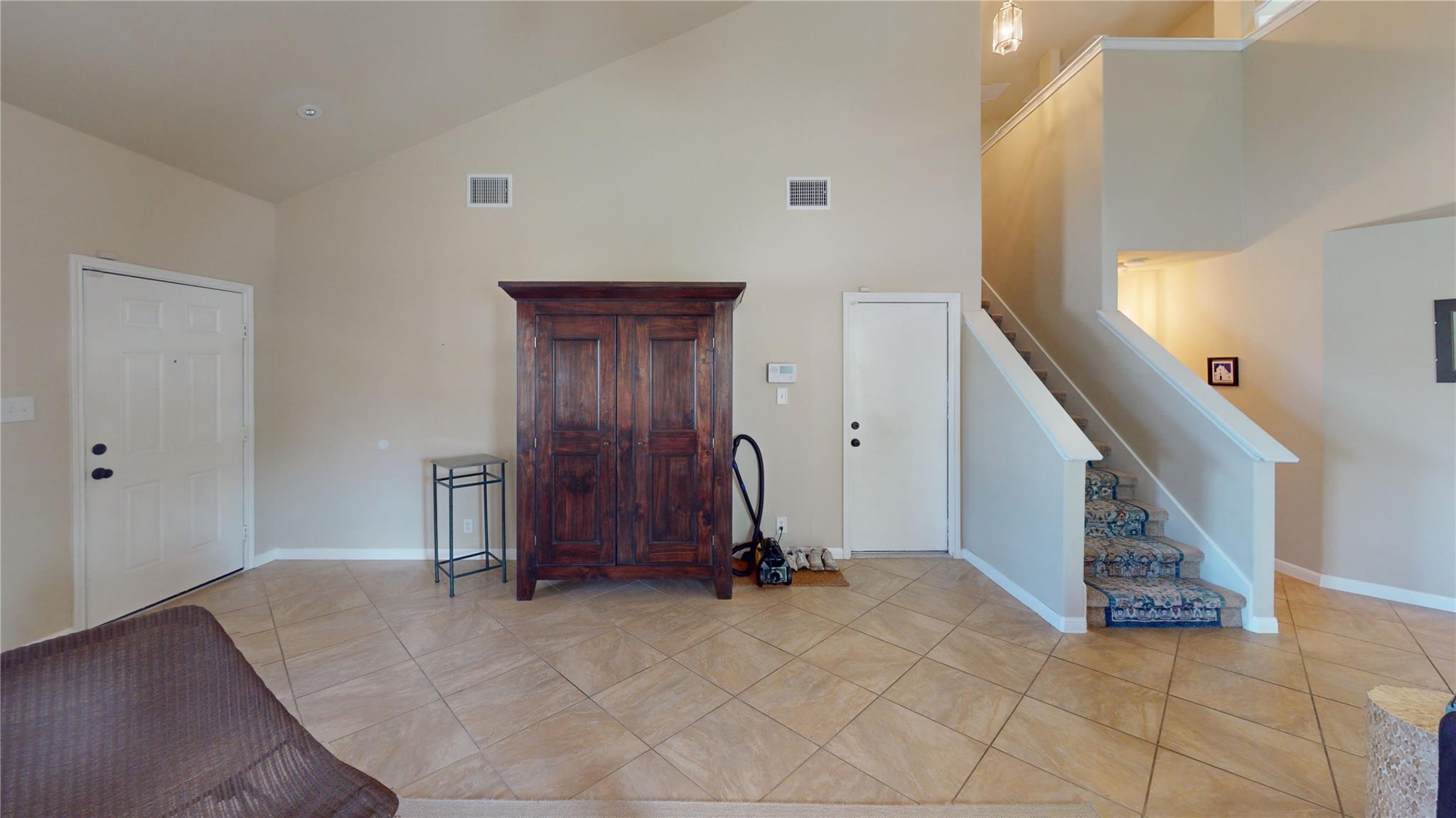 Vaulted ceiling entry with neutral-toned walls, t