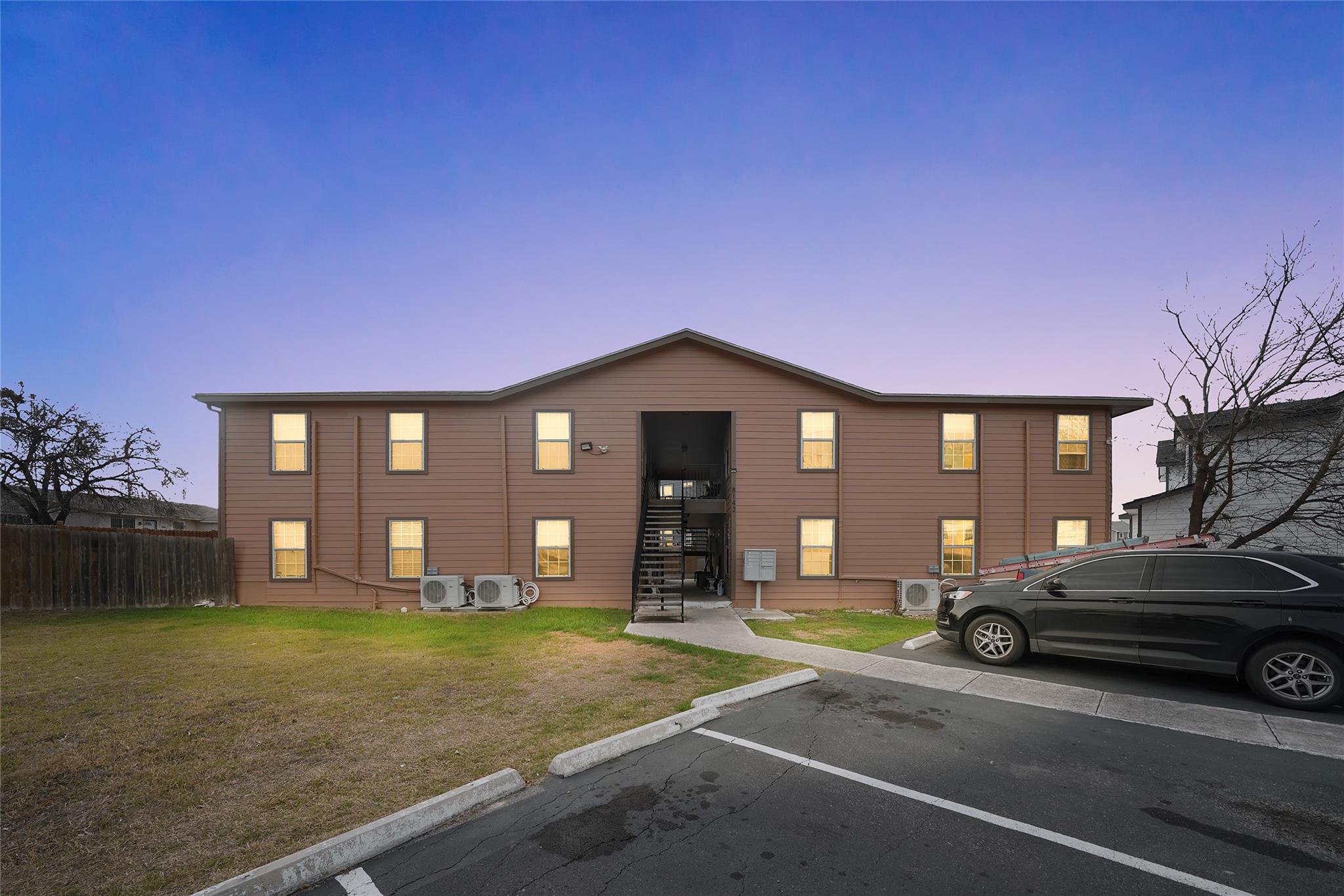 View of property with uncovered parking and stair