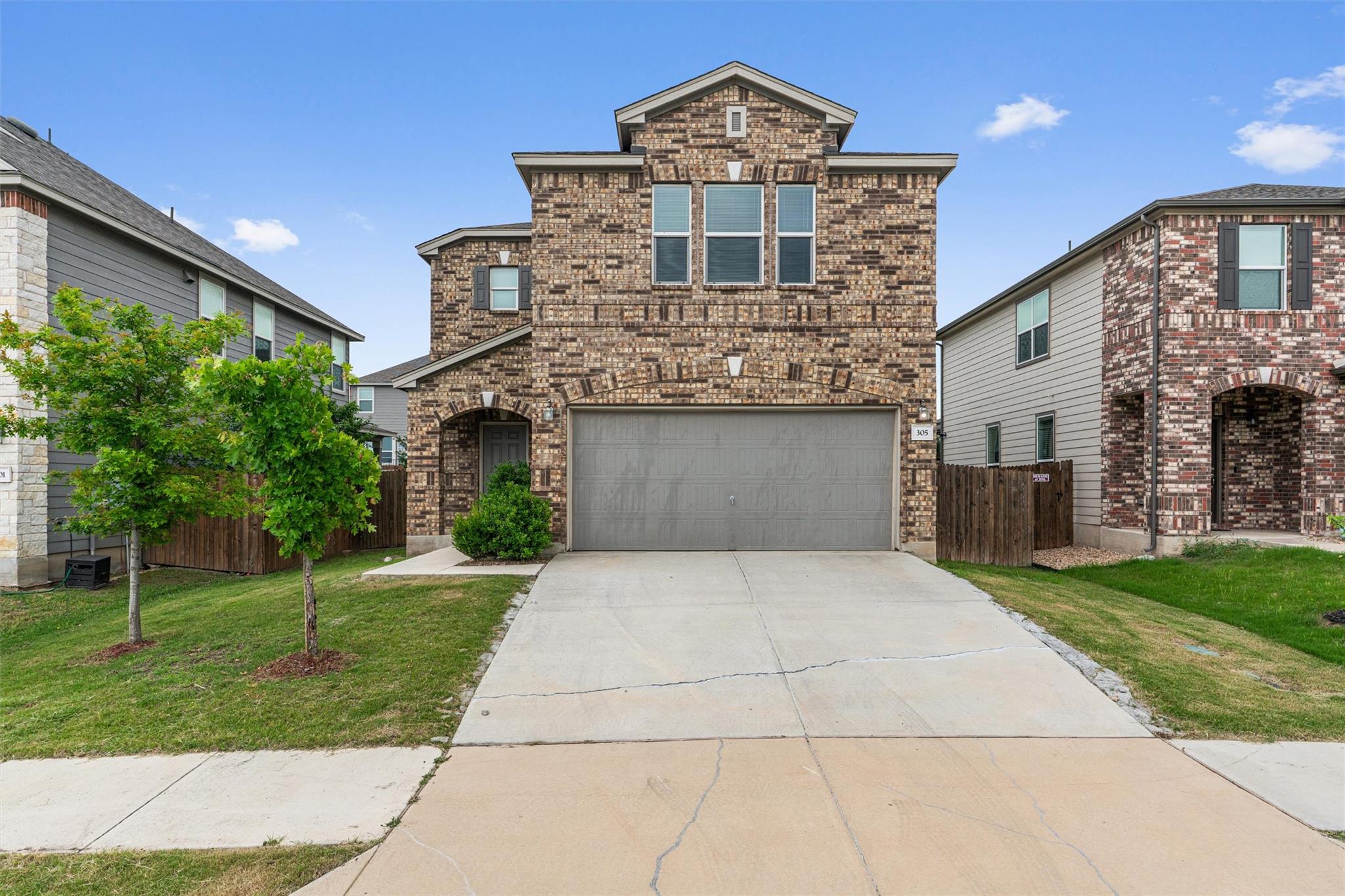 View of front facade featuring concrete driveway, an attached garage, and brick siding
