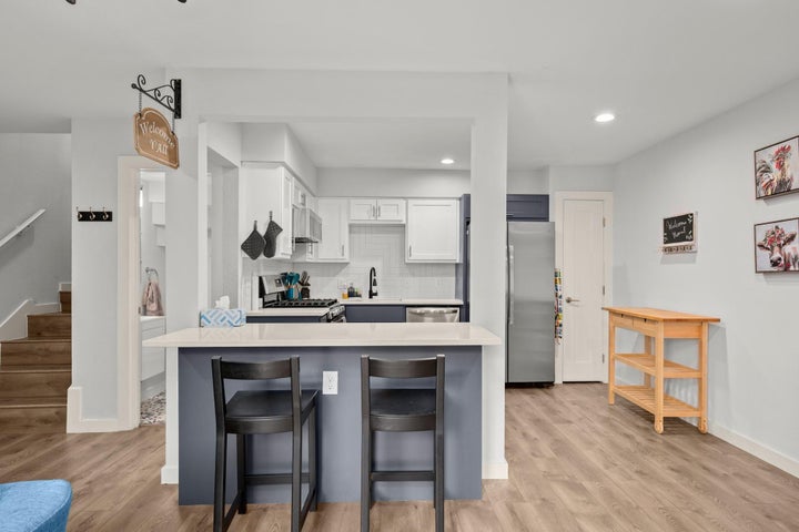 Kitchen featuring appliances with stainless steel finishes, a kitchen bar, light countertops, and recessed lighting