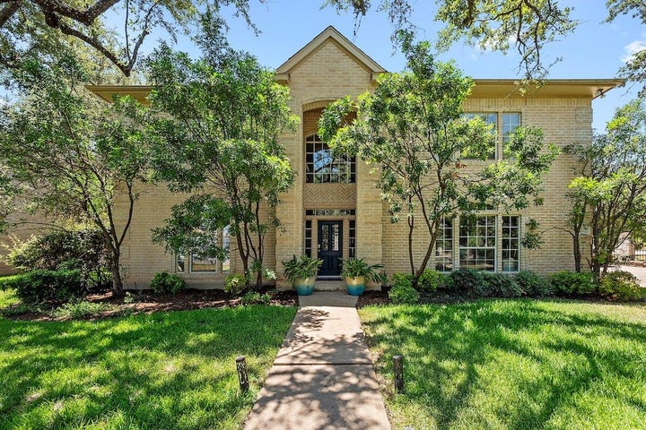 Traditional home featuring brick siding and a front lawn