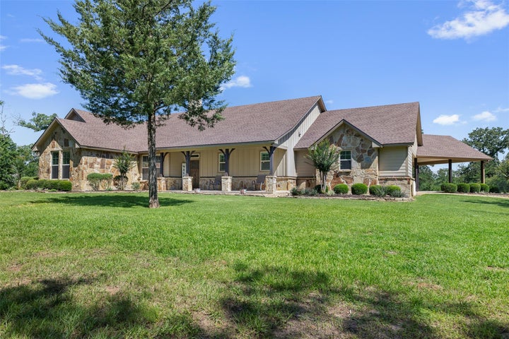 Stone and siding exterior with a covered front entry and a covered carport