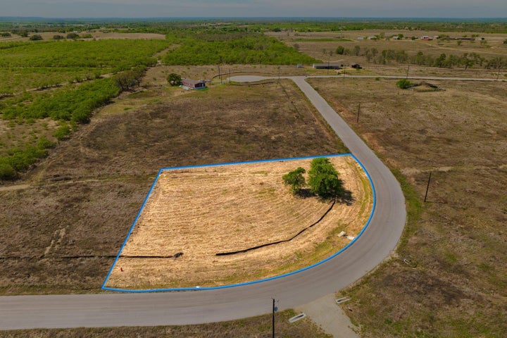 Acreage parcel with a paved road frontage, defined property boundary, and established trees