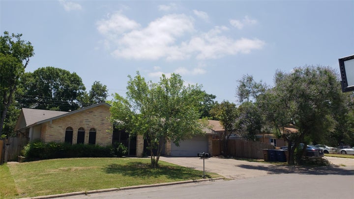 View of front of home featuring driveway, brick siding, and an attached garage