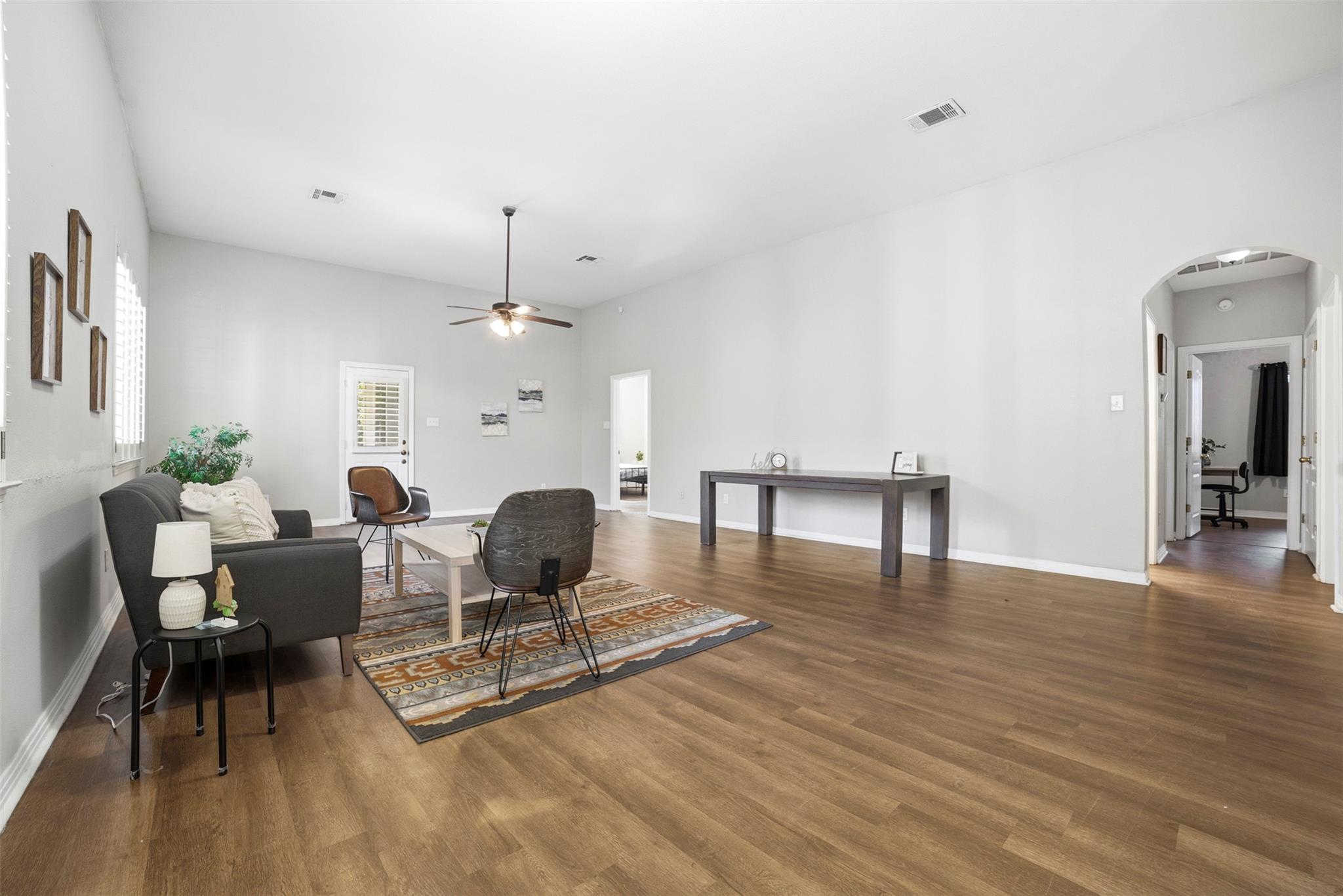 Living space with arched walkways, dark wood-style flooring, and ceiling fan