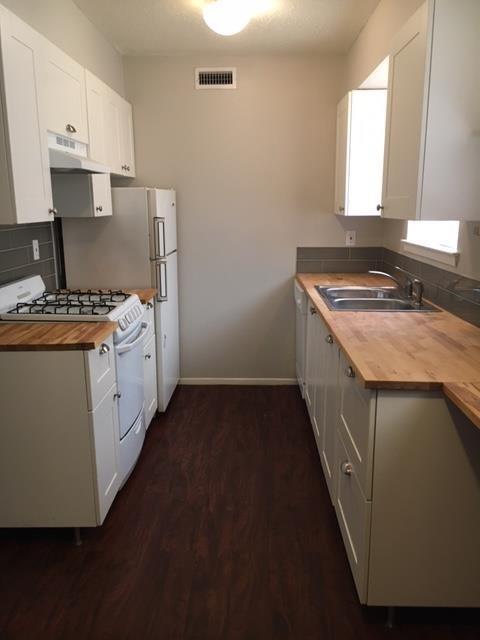 Galley kitchen featuring wood-finish countertops,