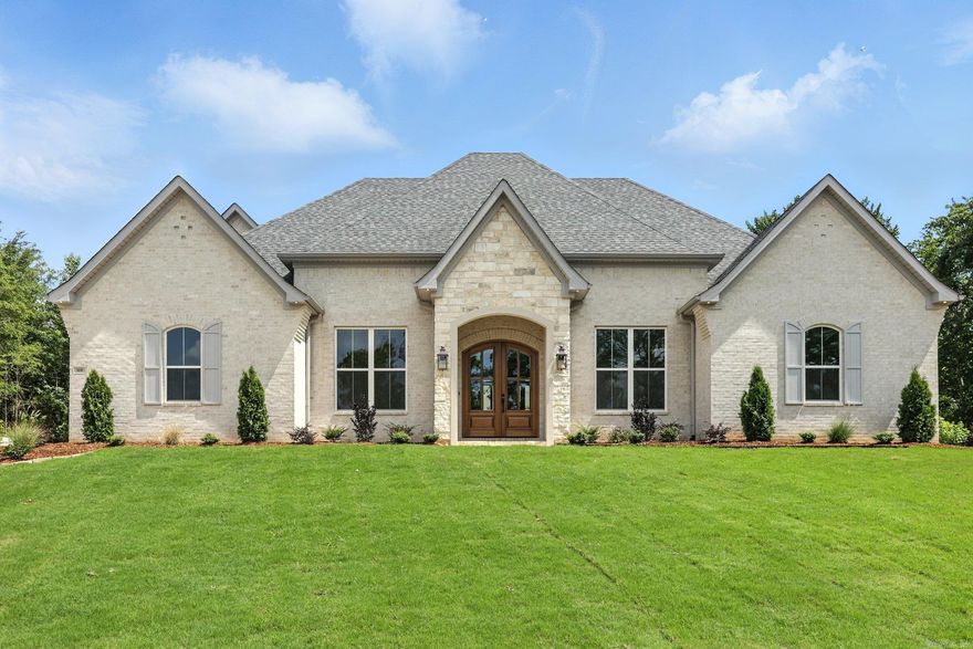 Welcome to 908 Cimarron Cove – A Stunning French Country Retreat in the Heart of Benton!  With nearly 3,000 square feet of thoughtfully designed space, this 4-bedroom, 4-bath home blends elegance, comfort, and custom craftsmanship in every corner. From the flared brick front and rocked arch entryway to the double arched mahogany front doors and stamped concrete circle drive, this traditional French Country home offers true curb appeal.  The spacious layout includes an upstairs bonus room, separate formal dining, and a large living area with vaulted ceilings, a decorative beam, and a beautiful arched built-in with white oak cabinetry flanking the rock-accented fireplace. A second fireplace awaits on the covered back porch, perfect for year-round enjoyment. The gourmet kitchen features a professional range with pot filler, farmhouse sink, quartz countertops and backsplash, custom vent hood, glass-front cabinetry above the beverage area, an island with an extra oven and microwave, and a large walk-in pantry with custom shelving. This home is truly custom in every sense – from the trim work in every room to the thoughtful layout designed for both beauty and function.