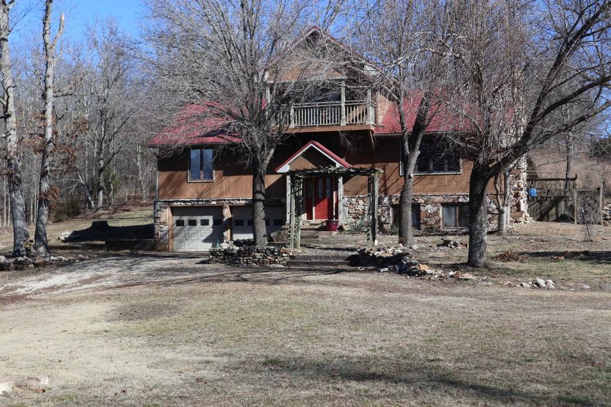 Experience the ultimate Ozark retreat: a stunning 3,000+/- sq. ft. country traditional home set on 20 m/l acres in Mammoth Spring, Arkansas. This multi-level residence features a striking native stone foundation, natural wood siding, & a durable metal roof, perfectly blending rugged aesthetics with modern comfort. The home offers ample space for family living, including a partially finished walk-out basement and an attached two-car garage with stone-wrapped pillars that provide room for a workshop. Outdoor enthusiasts will appreciate the  second-story balcony and covered front porch, ideal for taking in views of the  rolling terrain.  The property is ideal for those seeking a self-sustaining lifestyle or a hobby farm, boasting a mix of cleared land, mature timber, & a small pond. Equipped with a private well and septic system, this estate offers true seclusion and privacy while remaining minutes away from Mammoth Spring State Park and the world-class trout fishing and kayaking of the Spring River. Whether you are looking for a permanent "forever home" or a weekend getaway, this rare combination of acreage and square footage provides a unique opportunity in the heart of the Ozarks.