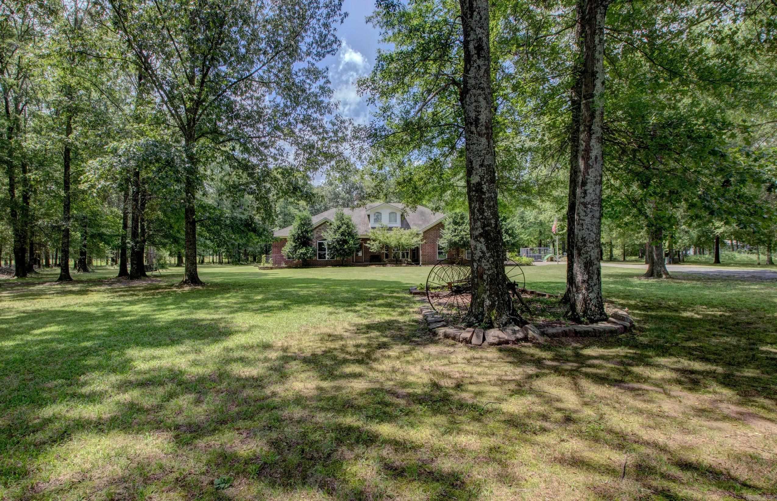 This charming and versatile 4-bedroom home—easily used as 3 bedrooms with a dedicated office—sits on 3.13 serene acres surrounded by mature trees and backing up to a wooded area for ultimate privacy. Inside, you’ll find an oversized living room with a cozy fireplace that flows into a formal dining room, complete with a built-in china cabinet. The kitchen is a dream with its bay window, generous island, walk-in pantry, and abundant counter space and storage. The expansive primary suite is a luxurious retreat, showcasing a spacious walk-in closet, relaxing jetted tub and walk-in shower. The fourth bedroom features a beautiful wood vaulted ceiling and built-in shelving, making it an ideal space for a home office or study. Step outside to take in the peaceful setting from the spacious front porch or entertain on the large back patio. The property also boasts a massive shop with lean-tos on each side, RV hookups, and a storm shelter—offering both comfort and practicality in a gorgeous country setting.