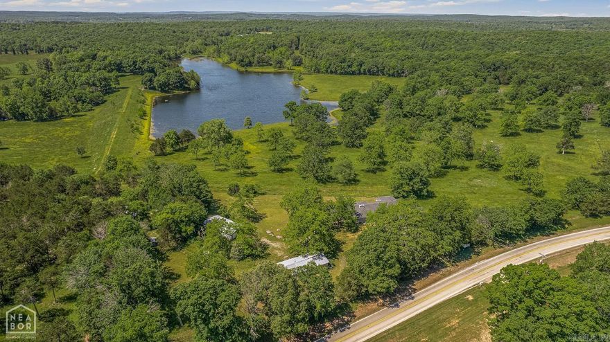 Looking for acreage in a beautiful natural setting? This 152 acre property offers a rare opportunity in Northeast Arkansas, featuring a scenic setting that includes a Corp of Engineers lake. The property includes a single family home, workshop, guest house with double garage, storage building, and a barn. The land offers a mix of rolling terrain, open pasture previously used for cattle, wooded areas, and fencing throughout portions of the property. The home features a covered porch connecting the residence to a detached two-car garage. Inside, the spacious living room includes a fireplace and floor to ceiling windows with views of the lake. The kitchen and dining area are located just off the main living space, along with a laundry room and half bath. Down the hall are two secondary bedrooms, a full guest bath, and a primary suite with private bath. This property offers a peaceful, rural setting with opportunities to enjoy the outdoors and nature.