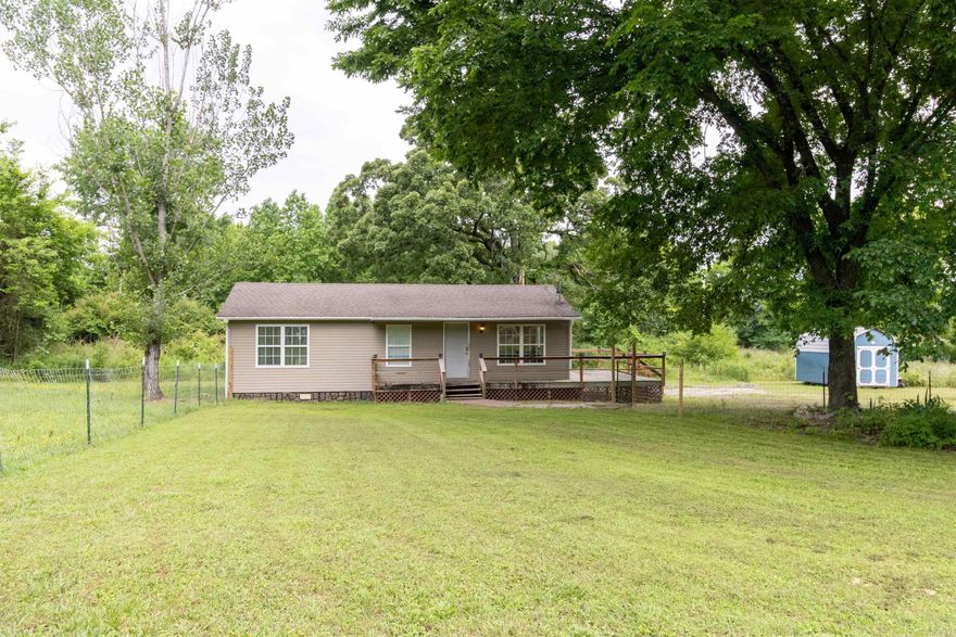 This updated 3-bedroom country home just down the road from Arkansas River access is move-in ready inventory for a first-time buyer, downsizer, or weekend angler who wants river access without paying river-frontage prices. The kitchen has been refreshed with white cabinets, butcher block counters, a live-edge bar-top island, tile backsplash, and a full stainless appliance package. Wood-look LVP flooring, crown molding, and recessed lighting run throughout the 960-square-foot open floor plan, giving the combined living and kitchen area a finished feel that is rare in this price range. A dedicated indoor laundry room sits off the main hallway. Outside, a fence wraps the front yard, mature shade tree covers the lot, and a brick paver walkway leads to the front porch. The storage building in back stays with the property. Central HVAC, vinyl siding, and stone-look skirting keep ongoing maintenance low. Hartman sits in Johnson County, with the river boat ramp and fishing access only minutes away.
