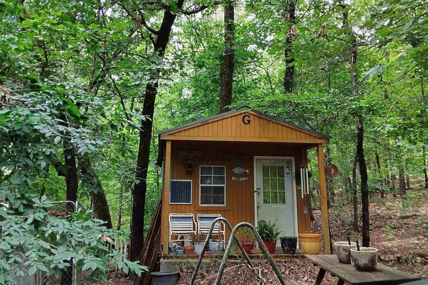 Escape to your own private retreat on 5.5 wooded acres in the peaceful, rural area of Hardy, Arkansas, nestled in the foothills of the Ozarks. This property offers the ideal weekend getaway, situated conveniently near the Spring River, several lakes, historic downtown Hardy, and Mammoth Spring State Park. The land is fully wooded with gravel county road frontage and includes a small cabin, a camper, and a couple of storage sheds. It’s equipped for off-grid living with existing solar power and rural water, though traditional electricity is also available at the road. This unique offering is currently being used as a writer's retreat but would be perfect for preppers or those seeking an off-grid lifestyle, with back-to-nature simple amenities; or with some clearing, could easily be transformed into a charming hobby farm.