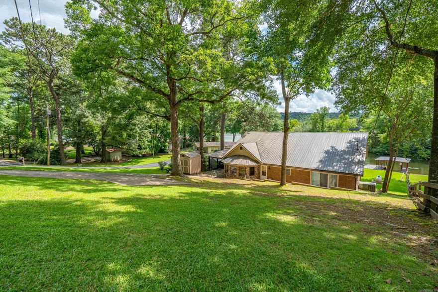 Descending the driveway to the carport, outdoor living is enhanced with a back patio along with a tucked away back porch and a level lot that leads gently to the water and a covered one-slip boat dock with an attached swim dock. This retreat is in plain sight of the main channel with great views while remaining protected from heavy wave action. A partially fenced backyard adds a little privacy AND a safe haven for your fur babies! From the carport you can reach the upper deck that offers massive insight to the area. From this deck you enter the sophisticated main cave. Behind this fun area, there is a large floored attic. The recently updated interior offers TWO master suites and a very large office/game room.  This home blends thoughtful design, comfort and serene lakefront living.  *Pictures made during drawdown. *No flood insurance required.