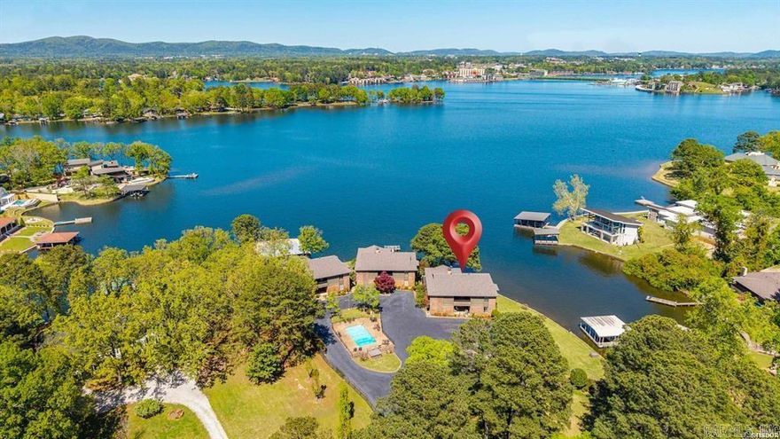 xperience one of the most captivating views on Lake Hamilton. From the moment you enter through the private gate to your first step inside, you’re met with a setting that immediately impresses.  This rare offering in the exclusive Shadow Hill community features just three buildings, each with only two residences, creating an intimate and private lakeside retreat.  Designed to take full advantage of its surroundings, the spacious balcony provides front-row views of the lake and seasonal fireworks displays. A covered boat dock is included, offering effortless access to the water, while the community pool offers a perfect place to relax.  The residence also includes an assigned covered parking space for added convenience and protection.  Inside, the large living room is highlighted by vaulted ceilings, creating an open and airy feel that enhances the home’s sense of space and light. The dining room is equally impressive, offering beautiful lake views that make every meal feel special. The updated kitchen flows seamlessly into the living and entertaining areas, complemented by a wet bar complete with an ice maker and wine cooler.