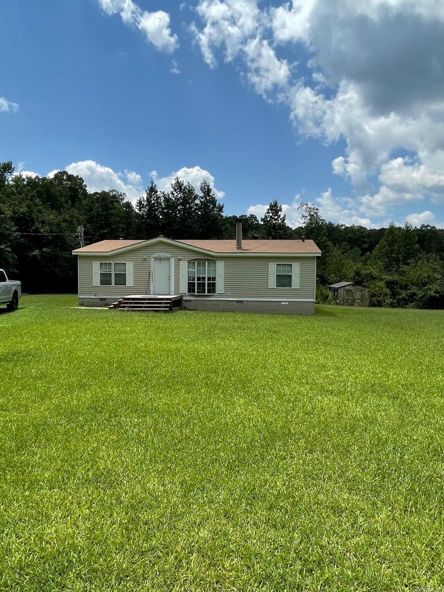 Looking for easy access to Little Rock and Pine Bluff, well here it is!  Just off I-530, this double wide is on a permanent foundation and has a cinder block base.  It sits back off the road allowing for more privacy with a nice sized deck on the front.  There's a side door with steps that will enter into the laundry room, which leads into the kitchen for easy unloading of groceries.  There is ample storage and counter space in the kitchen.  There is no carpet in this residence, it's all linoleum.  The living room is large with a wood burning fireplace  The primary bedroom is separate from the other two and has a garden tub for soaking.  The other two bedrooms are basically the same size and share a smaller bathroom.  There is a 12x22 well built deck on the back that was constructed in 2022 and is great for entertaining.  Enough land has been cleared to enjoy a nice lawn in the back.  So nice, you'll find deer grazing on it.  A 10x15 shed is also on the property for extra storage.  Roof was replace by the previous owner in 2019.  The house has been cleaned by the Entergy program in 2021.  Most of the lights have been converted to LED.  Agents please see remarks.