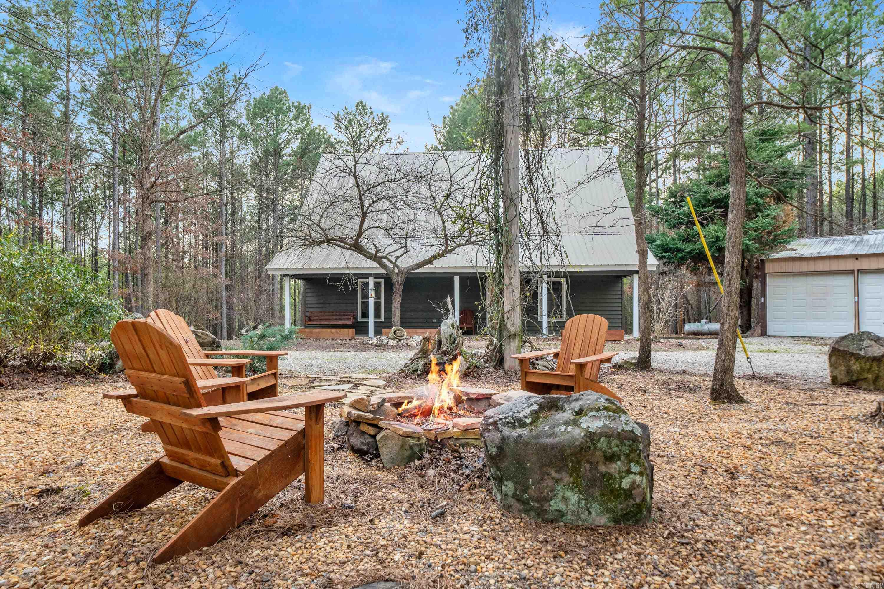Escape to your own private sanctuary with this beautifully updated custom-built cabin on 3 secluded acres bordering the Ouachita National Forest. Just minutes from Lake Ouachita, this charming retreat is surrounded by soaring trees offering the ideal blend of comfort and adventure. Recently painted exterior, this 2br, 2ba cabin exudes charm with its warm natural wood interior from floor to ceiling, creating an inviting atmosphere. The open-concept kitchen, equipped with SS appliances, and living area provide a seamless space for entertaining or relaxation. Upstairs are a spacious loft bedroom & sitting area with private bath & luxurious soaking tub. Step outside to enjoy the ultimate in outdoor living. Gather around the fire pit or cook up a feast with a fully equipped outdoor kitchen, complete with grill, authentic pizza oven, & BBQ smoker. Outdoor enthusiasts will appreciate the properties easy access to all the National Forest has to offer. Lake Ouachita offers world-class boating, fishing, and swimming. Additional features include whole home generator, as well as a 30x50 garage/shop, big enough to house all your toys & a home workshop. Adventure and relaxation awaits.