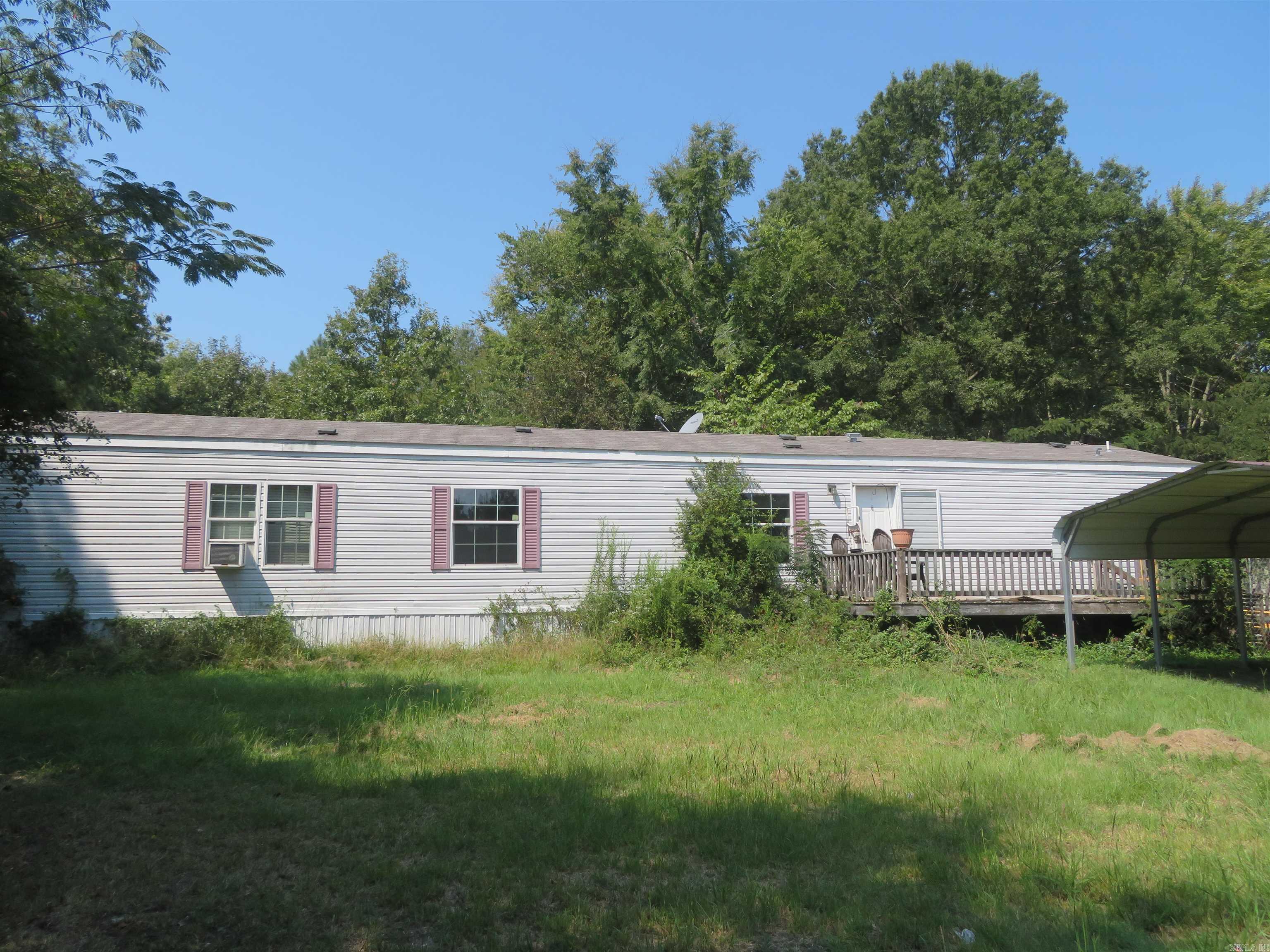 Approx. 5.2 ACRES mostly wooded, a Mobile Home (17'3" x 76') manufactured in Aug. 2012 with entry deck & a nice 'covered' rear/back porch (10' x 24') --- plus a detached, frame storage bldg./shop bldg. (12' x 24'), a detached 'store-bought' metal, double carport (18' x 20'), & a small pond that is surrounded by trees/woods. This Parcel of land boasts 523 linear feet of frontage on the old Hwy. 67 South Highway (which runs parallel to the present Hwy. 67 South) between Gum Springs and Curtis. This Property happens to have an older structure on the front Northeast corner (of Subject Property) that is in need of repair --- if someone is interested in having a larger 'shop building' since this 5.2 Acres offers the owner 'highway frontage' advertising, 24/7 --- for someone who might want to work from home & desires passers-by as a potential customer base. Awesome! The mobile home on this small acreage Tract of Land is only 13 years of age. Its interior is VERY ATTRACTIVE! And the floor plan is VERY DESIRABLE! 3-BR's, 2-BA's. Approx. 1,311 SQ. FT., heated/cooled. Separated BR arrangement (Primary-BR/BA on 1 end). APPEALING kitchen/dining/living combination! SOME REPAIR needed.