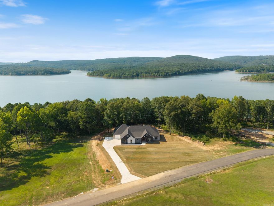 Over one acre Lakefront Lot! Enjoy the views of the lake from the big covered back porch with a vaulted tongue & groove wood ceiling. A large deck will be added for even more outdoor entertaining space. There will be room in this backyard if you wanted to add a pool later. The home is open concept with cabinets in the kitchen to the 10 ft. ceilings. The pantry is huge & will be hidden behind the cabinet doors in the kitchen cabinets. Will have a massive island with the sink in the island. The living room has a vaulted ceiling that carries out to the back porch. You will love the windows with the views of the lake. The laundry is oversized with lots of cabinets. From the laundry room you can enter the primary closet with more room than you will have clothes for. From the closet you can enter the primary bathroom. Separate tile shower & soaking tub and dual vanities. Primary bedroom is separate from the 3 guest bedrooms. Luxury vinyl flooring throughout. Lockers as you come in from the garage. The 3rd bay of the garage is extra deep (35 feet) to stow all of your lake toys and your boat.  There is also room on this lot to build a shop. This subdivision is brand new. All new homes here