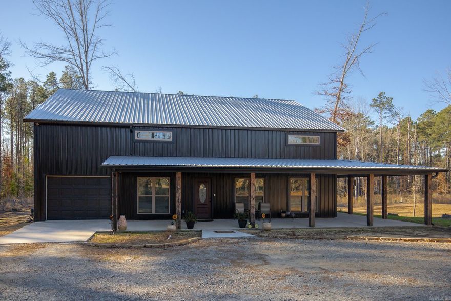 Welcome to your dream Barndo on 5.17 acres! This custom home offers 3,760 sq ft of heated and cooled living space plus garage area, all sitting on a 40x50 slab and stick built with 2x6 framing and durable metal siding. Inside you’ll find 3 bedrooms, 3 full bathrooms, an office and 2 bonus areas. The primary suite is downstairs along with an additional full bath for guests. Office space, walk in pantry and laundry are downstairs also. Upstairs features 2 bedrooms (walk in closet) and a bathroom with two bonus room areas (with closet) The kitchen was designed to impress with black granite countertops, farmhouse apron sink, touchless faucet, stainless vent hood, gas stove, and a large walk-in pantry with room for freezers. Enjoy cozy evenings by the natural stone gas fireplace with concrete hearth. Built for efficiency and comfort, this home includes spray foam insulation, separate controlled upstairs HVAC with built-in humidifier, gas tankless water heater, and a wired commercial-grade security system. Relax on the wraparound porch supported by beautiful Douglas fir posts and enjoy peaceful country living just minutes from town. The 1-car garage/shop space adds flexibility