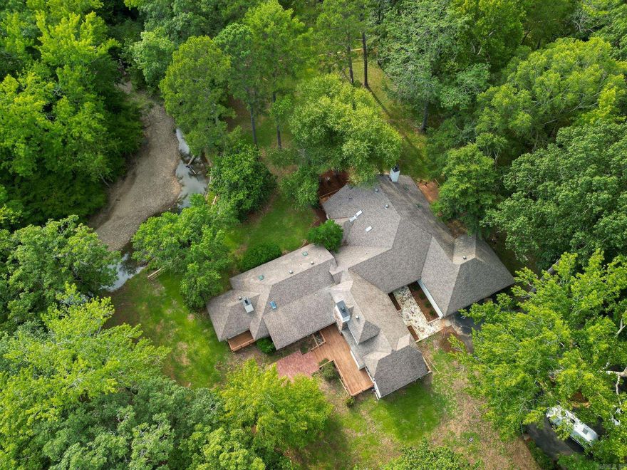 Discover peace and luxury on 10 acres with the Little Maumelle River winding through your backyard, a mountain hillside beyond the creek, and a tranquil front pasture. This 4-bedroom, 4.5-bath home has been beautifully remodeled, blending comfort with elegance. The gourmet kitchen features two islands, perfect for gathering, while three fireplaces and abundant skylights fill the home with warmth and natural light. Every bathroom has been updated with stunning tile, and the master suite is a true retreat—boasting a freestanding tub and an oversized shower with a rain shower cascading from a skylight above. Whether you’re savoring morning coffee on the porch or exploring your private riverbank, this property offers a lifestyle of serenity and sophistication.