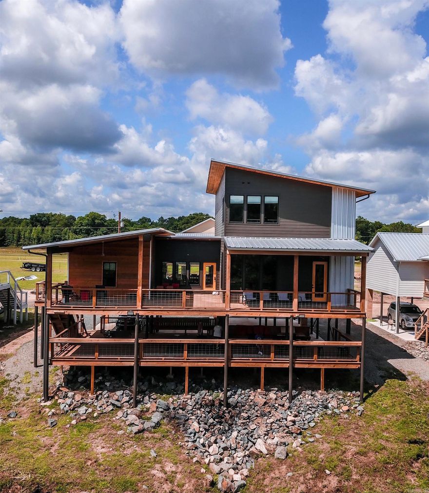 LUXURIOUS RIVERSIDE RETREAT!  "THE MODERN" overlooks the Caddo River and is a successfully ran and operated nightly rental that has proven to be an income producing venture with it's lavish touches, modern design, and upscale finishes! Property offers 5 bedrooms, 5 bathrooms, a game room, a kitchen designed with entertaining in mind, bunk room, coffee bar, and so much more! Cabin has over 3700 sq ft of living space, can sleep 17, has two riverside balconies, river frontage and river views, and is located in a private, gated community! Property has a yearly revenue of approximately $95,000 - $115,000! Escape to your own riverfront oasis, continue the successful rental business, or do both! The choice is yours!