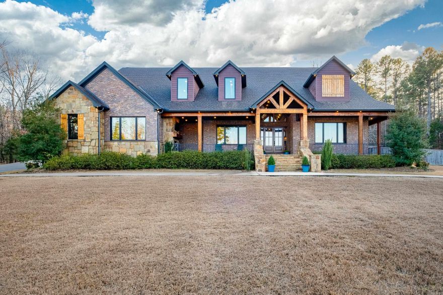 Experience refined lodge-style living in this exceptional custom home set on 5.05± private acres, masterfully built by Tim Hughes. Thoughtfully designed with craftsmanship at every turn, the interior features oversized solid wood doors, custom cabinetry throughout, and a dramatic stacked rock accent wall in the formal dining room. The open-concept living, dining, and kitchen spaces are ideal for entertaining, anchored by a chef’s kitchen with four KitchenAid Professional Series ovens, a gas range with griddle, and abundant storage. Specialty spaces include a library/office with cozy reading nook, a professional-grade theater room with a 200-inch screen and SVS sound system, a craft room with padded commercial flooring, and a fun bunk/sleepover room. Two laundry rooms, a dog washing station, and exceptional storage add everyday convenience. Outdoor living shines with a covered front porch featuring a fireplace, a spacious screened porch with outdoor kitchen, greenhouse, and ten raised garden beds. Additional highlights include a heated and cooled four-car garage and two whole-house generators—offering luxury, comfort, and peace of mind in a truly one-of-a-kind setting.