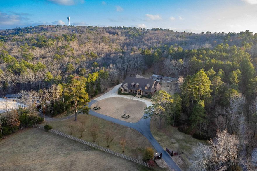 Experience refined lodge-style living in this exceptional custom home set on 5.05± private acres, masterfully built by Tim Hughes. Thoughtfully designed with craftsmanship at every turn, the interior features oversized solid wood doors, custom cabinetry throughout, and a dramatic stacked rock accent wall in the formal dining room. The open-concept living, dining, and kitchen spaces are ideal for entertaining, anchored by a chef’s kitchen with four KitchenAid Professional Series ovens, a gas range with griddle, and abundant storage. Specialty spaces include a library/office with cozy reading nook, a professional-grade theater room with a 200-inch screen and SVS sound system, a craft room with padded commercial flooring, and a fun bunk/sleepover room. Two laundry rooms, a dog washing station, and exceptional storage add everyday convenience. Outdoor living shines with a covered front porch featuring a fireplace, a spacious screened porch with outdoor kitchen, greenhouse, and ten raised garden beds. Additional highlights include a heated and cooled four-car garage and two whole-house generators—offering luxury, comfort, and peace of mind in a truly one-of-a-kind setting.