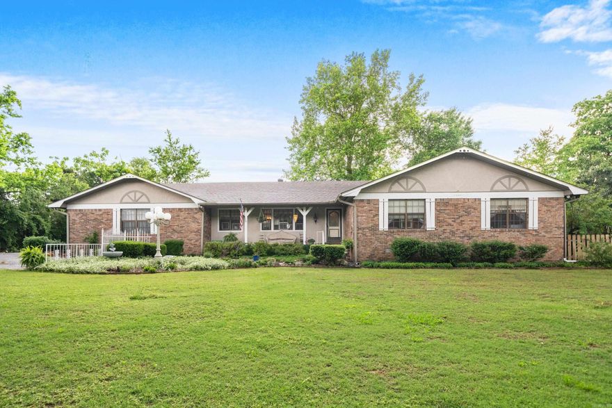 Enjoy privacy and seclusion on 2.9 fully fenced acres within the city limits. Mature cypress trees provide a peaceful, park-like setting. This singel level, 4-bedroom, 4.5-bath home includes en suite bathrooms in every bedroom, a formal dining room, and a spacious hearth area with a wood-burning stove and built-in wood storage-perfect for cozy gatherings. The bonus room, complete with a wet bar and full bath, offers flexible space for a fourth bedroom, home office, or game room. Step outside to a covered patio that invites outdoor living. The property also includes a 24x48 workshop/utility building with four bay doors, an RV hookup with electricity and sewer, and a secure dog run. A rare find that combines space, function, and natural charm—all within the city limits.