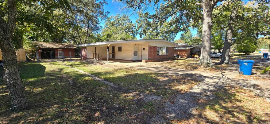 Charming brick home in a quiet, established neighborhood! This 3-bedroom, 2 bath home offers 1,218 sq. ft. of single-level living on a shaded 0.22-acre lot. Spacious living area with neutral carpet, ceiling fans, and plenty of natural light. Kitchen and dining areas are functional and inviting. Main bath features classic mid-century pink tile, while the primary suite includes an updated walk-in tile shower with bench, grab bar, and decorative inlay. Covered carport and concrete drive for easy access. Enjoy a fenced backyard with mature trees and a 22x24 detached frame garage/workshop—perfect for storage, hobbies, or projects. Conveniently located near schools, shopping, and dining. A well-kept home combining vintage charm with practical updates!