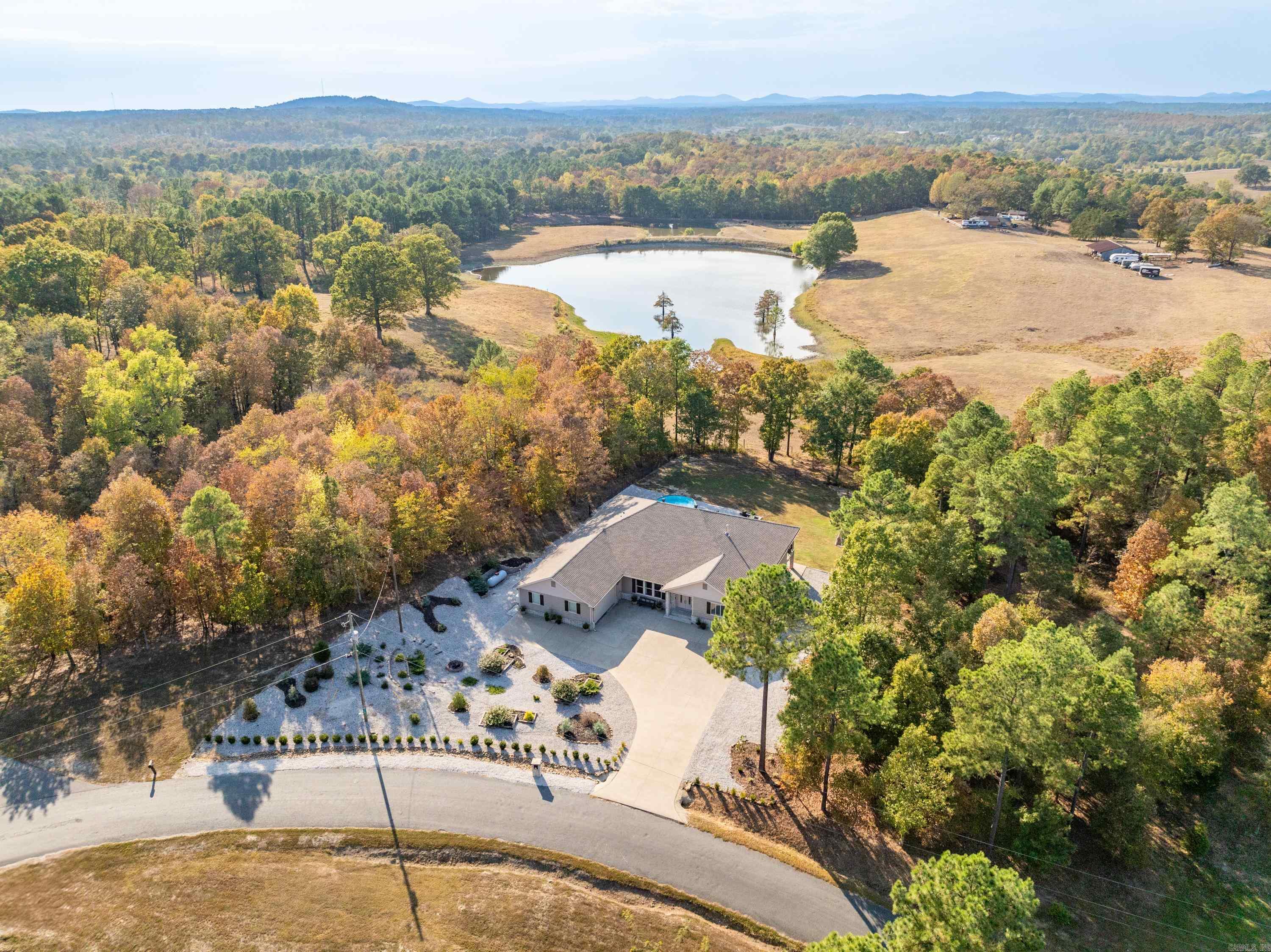 Located in a highly sought after neighborhood in Lake Hamilton School District, this stunning home has everything you could ask for. Nestled on 2+ private acres encompassed by soaring trees, you'll love the breathtaking views of the bordering pond & pasture from the expansive back porch. Open the front door, and you're greeted with fabulous custom features including tongue & groove ceilings, shiplap & rock walls, beautiful stacked stone, wood-look ceramic tile floors throughout, & glowing ambient fireplaces. The spacious, split floor plan features two master suites, one with an attached bonus room, walk-in tiled shower, a corner jetted tub, separate vanities & his/hers closets. The open kitchen is a chef's dream, with double ovens, abundant cabinetry, & a walk-in pantry. Don't forget the 450 sq. ft. heated & cooled workshop/bonus room below, offering tons of options and flexibility. Additional features include a low-maintenance front yard, a whole-home generator and water filtration system, a large fenced back yard with above-ground pool, a sprinkler system, & useable acreage with room to build a shop. See for yourself why this home is so special.