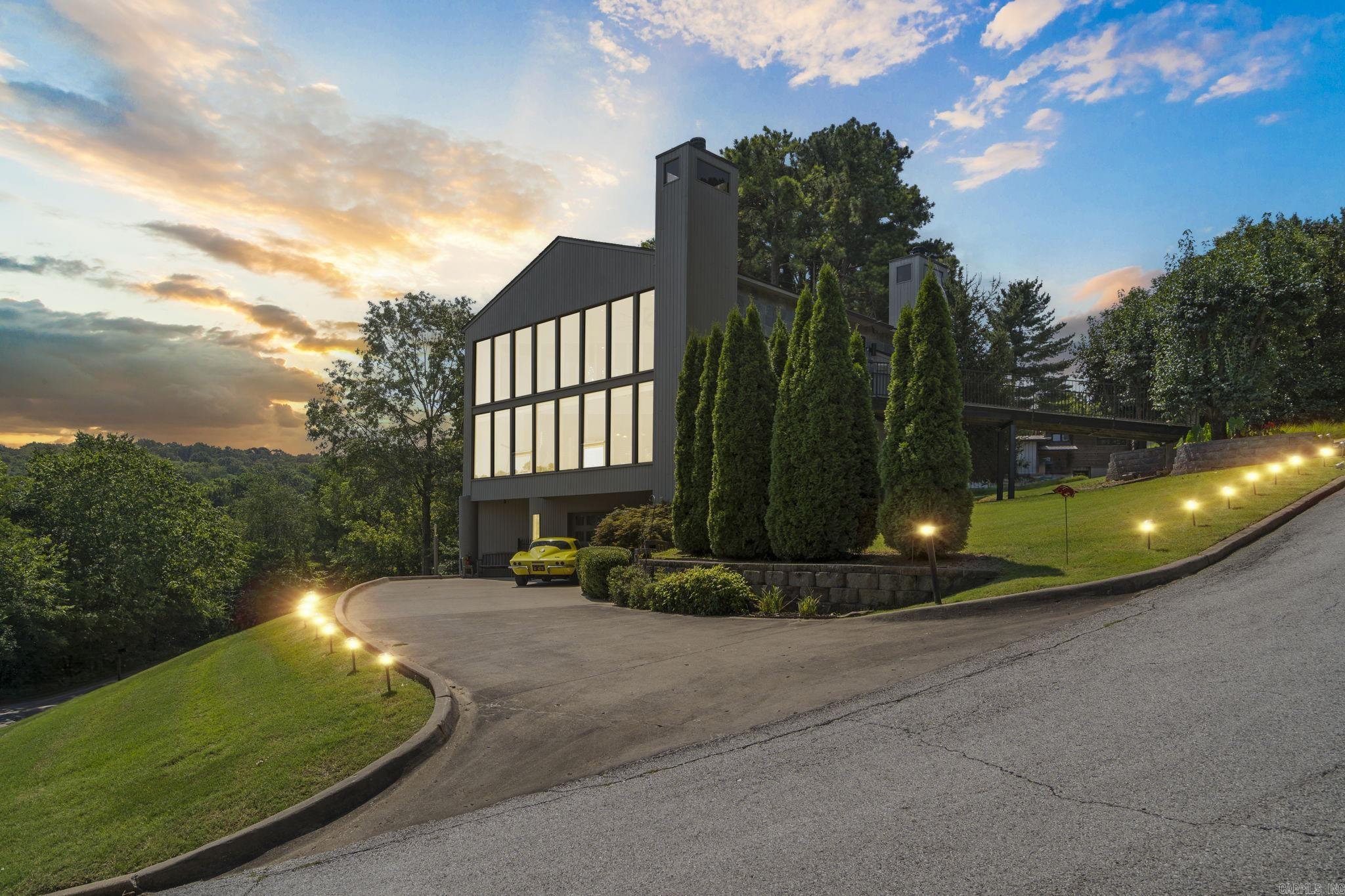Presenting the final architectural triumph of internationally acclaimed solar architect James Lambeth. Set on a serene half-acre lot with views of Lake Lucille in downtown Fayetteville, this custom home is a true original. It offers four spacious, elegantly finished bedrooms and two and a half luxurious baths. A large family room complements a versatile game/media roomāclimate-controlled for use as a garageāwith a built-in entertainment center. Unique amenities include a private three-story elevator, underground electric pet fence, soft water filtration, laundry chute, and a stunning second-story deck with street-level access. The chef-inspired kitchen, highlighted by a sleek bar, is ideal for entertaining. The living room features a dramatic two-story travertine fireplace and a 17-foot wall of windows with lake views. A spiral staircase, built-in media center, and wood-burning fireplace complete the space. The primary suite offers a marble-clad bath with freestanding tub, fireplace, and double shower. This home is living work of art. Schedule your showing today!