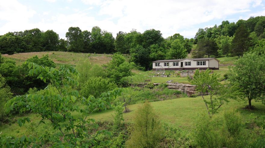 This 164.48-acre property offers live water, scenic views, privacy, a modern manufactured home, excellent hunting, and a rare mix of pasture and hardwood timber, all set in a private hollow with Ozark Mountain views.  The land features 7 natural springs, including one that creates a waterfall flowing into a year-round creek, along with 4 ponds, a drilled well, established trails, and an orchard with a variety of fruit trees. The 2021 manufactured home includes 5 bedrooms, 2 bathrooms, an open floor plan, updated appliances, spacious kitchen, walk-in closets, a large walk-in shower, and a soaking tub. A whole-house backup generator provides added security. Additional improvements include 3 shops (two 30x50 and one 30x40) with concrete floors, ideal for equipment, storage, or workspace. Wildlife is abundant, with deer, turkey, and black bear frequently seen. Highway 9 frontage offers easy access while maintaining privacy. Conveniently located minutes from the White River, under an hour to Norfork Lake, and about 20 minutes to Mountain View (home of the renowned Ozark Folk Center, live music, and year-round festivals), this is a one-of-a-kind Ozark property all for $734,900!