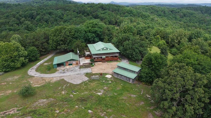 This 2,400 sq. ft. log home sits on 8 surveyed acres just off Hwy 9 South in the heart of the Ozarks. With mountain views and usable acreage, this property is well-suited for those looking to enjoy country living without giving up modern amenities. The two-story home features spacious living areas with large windows that bring in natural light and showcase the surrounding landscape. Interior highlights include walk-in closets, a walk-in pantry, on-demand water heater, natural gas, mini-split systems, city water, and septic. Outside, the covered wrap-around porch provides a comfortable space to relax and take in the views. There is also a designated area ready for a hot tub, making it easy to create your own outdoor retreat. The property is well-equipped for work or hobbies with two shops and an additional garage. One of the shops includes a car lift and large air compressor, offering a ready-made setup for mechanics, projects, or small business use. All appliances convey with the sale, making this home move-in ready. Priced at $349,900, this property offers a rare combination of acreage, functionality, and Ozark scenery.